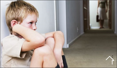 Niño triste sentado solo en el suelo de un pasillo escolar
