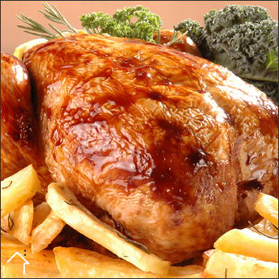 Pollo entero asado y dorado al horno con rodajas de limón y verduras en una fuente